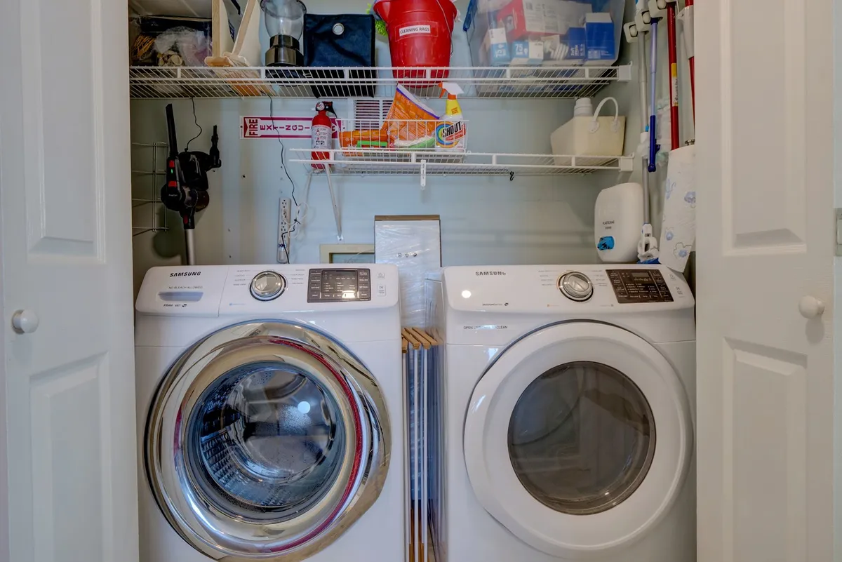 A practical laundry area featuring a modern washer and dryer set, with shelves stocked with laundry supplies. The space is tidy, well-lit, and functional, supporting the convenience of handling household chores during a vacation stay.